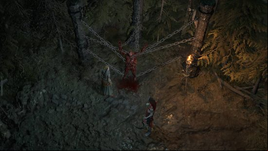 A chained up bloody corpse with two women having a discussion about it by lantern fire