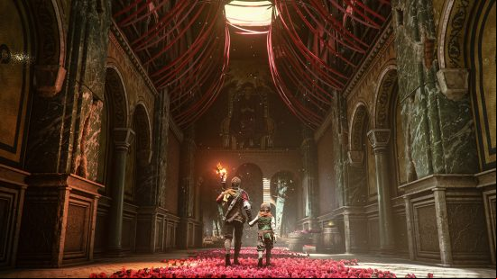 A young woman and a little boy holding hands walk on a red carpet made of flowers in a high, ornate building with the sun streaming down on them