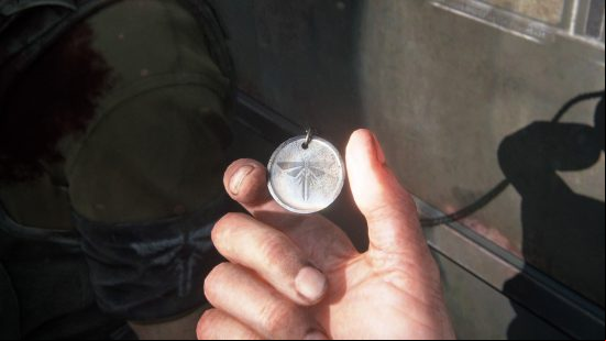 The Last of Us Firefly Pendants locations: a hand holds a dogtag-like pendant.