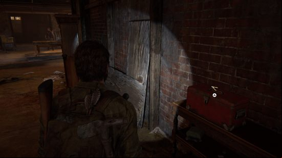 The Last of US workbench tool locations: a bearded man shines a flashlight down a dark corridor.