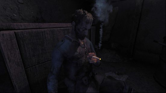 A WWI era soldier sits with his head slumped smoking a cigarette in a dark trench
