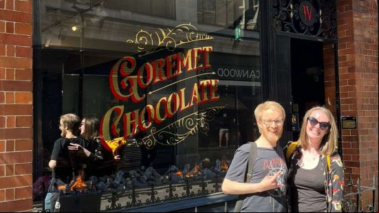 Diablo 4 chocolate shop - PCGamesN staff Ken and Lauren stand outside the Lilith & Co store.