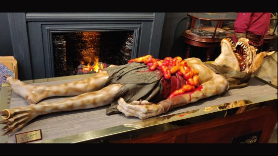 Diablo 4 chocolate shop - a chocolate model of a treasure goblin laid out on a table, rings on its fingers and toes and intestines spilling from its stomach.