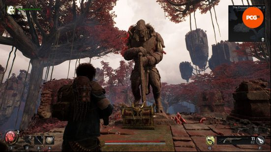Remnant 2 review: A Traveler approaches a statue of a faun-like being holding a greathammer with a loot chest at its feet.