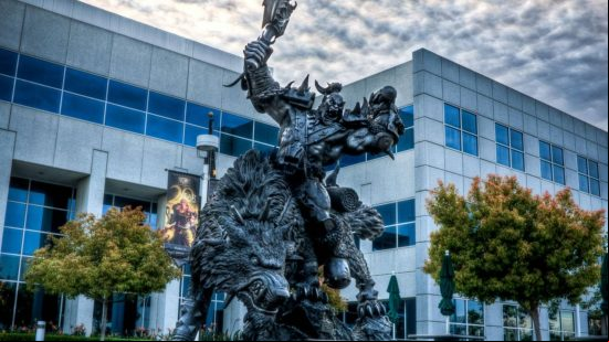 A huge black statue of an orc sitting on a snarling wolf in front of a white and blue office building
