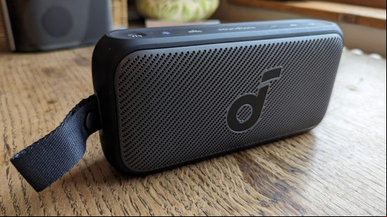 Anker Soundcore Motion 300 review: a black speaker with silver grille appears on a wooden surface.