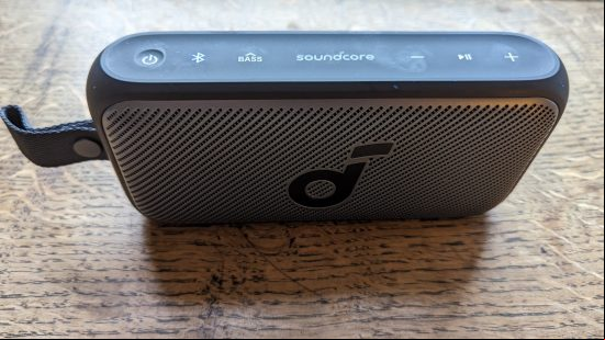 Anker Soundcore Motion 300 review: a black speaker with silver grille appears on a wooden surface.