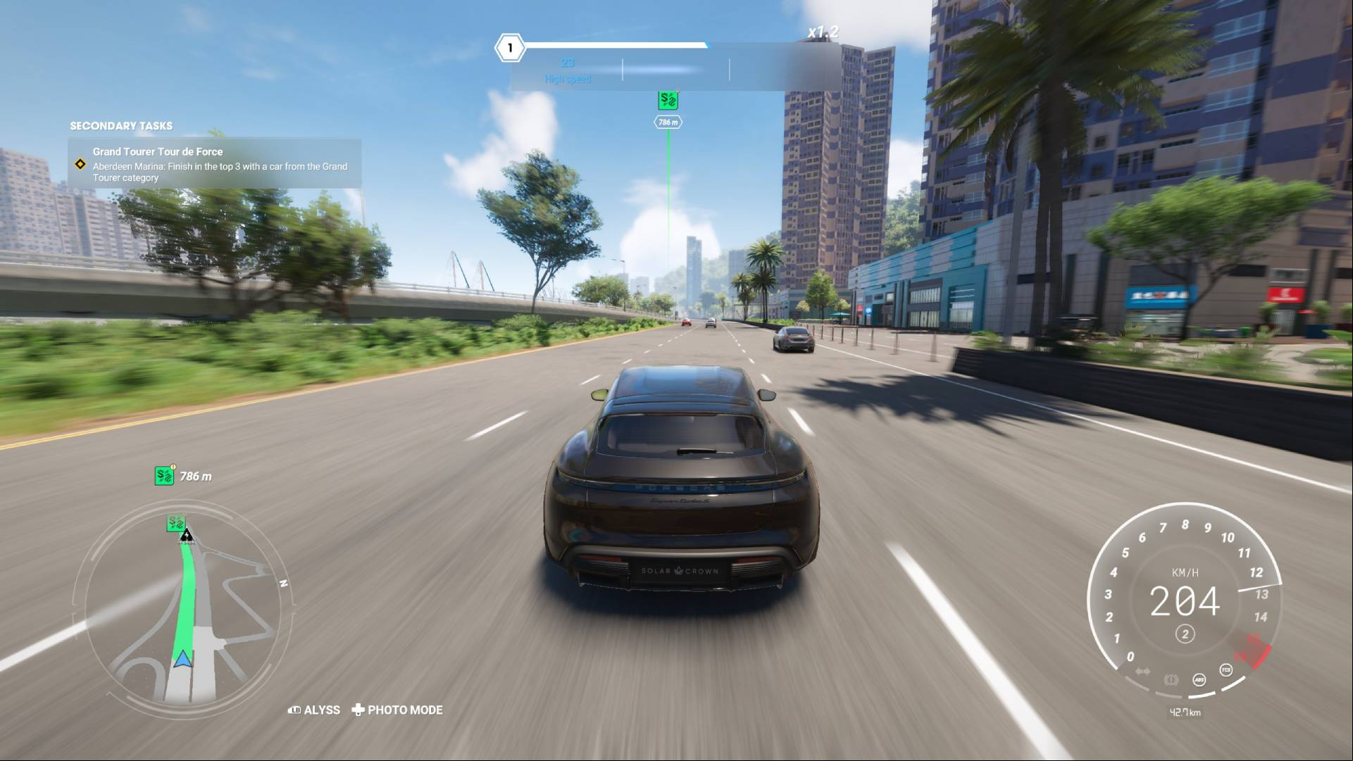 Driving a Porsche at high speed down a highway with trees on the left and buildings on the right.